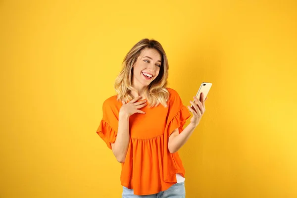 Mujer usando el teléfono móvil para el chat de vídeo en el fondo de color —  Fotos de Stock