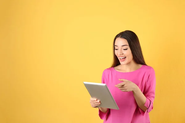 Mujer utilizando la tableta para el chat de vídeo en el fondo de color. Espacio para texto — Foto de Stock