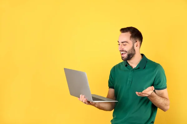 Człowiek za pomocą laptopa do rozmów wideo na kolorowym tle. Miejsce na tekst — Zdjęcie stockowe