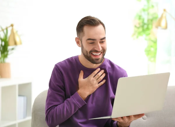 Mies käyttää kannettavaa tietokonetta video chat olohuoneessa — kuvapankkivalokuva