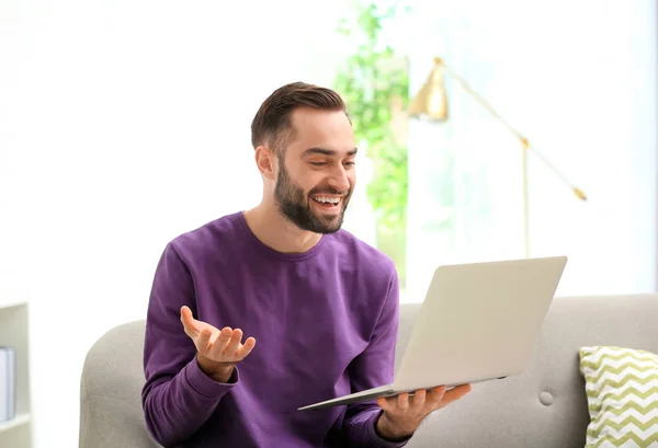 Człowiek za pomocą laptopa do rozmów wideo w salonie — Zdjęcie stockowe