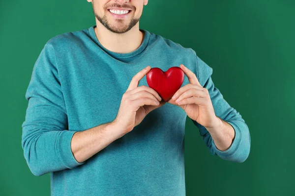 Hombre sosteniendo corazón decorativo sobre fondo de color, primer plano —  Fotos de Stock