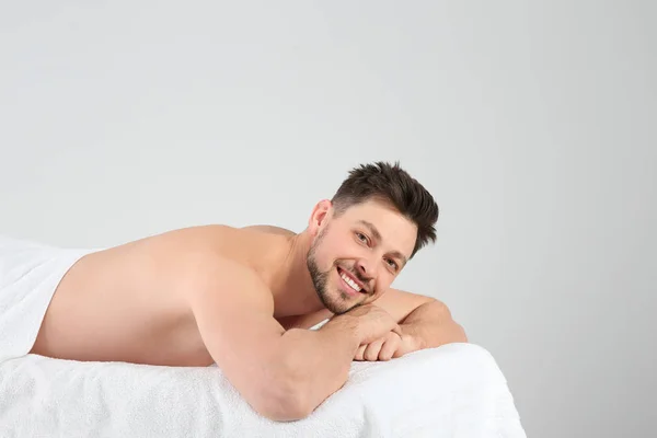 Homem bonito relaxando na mesa de massagem contra fundo branco. Serviço de Spa — Fotografia de Stock