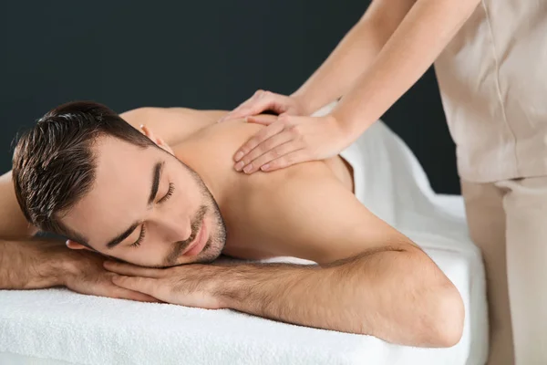 Bonito homem recebendo massagem nas costas em fundo preto. Serviço de Spa — Fotografia de Stock