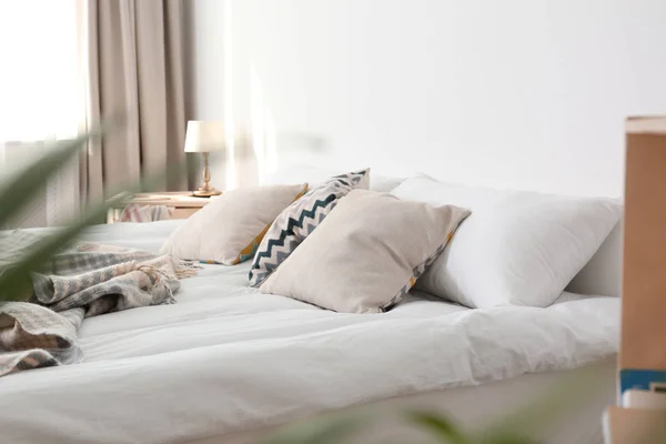 Κρεβάτι με μαξιλάρια και καρό κοντά στο φως τοίχο. Άνετο εσωτερικό σχεδιασμό — Φωτογραφία Αρχείου