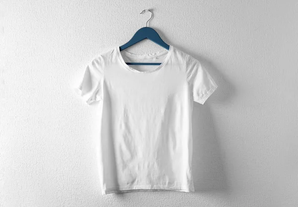 Kleiderbügel mit weißem T-Shirt auf hellem Hintergrund. Design-Attrappe — Stockfoto