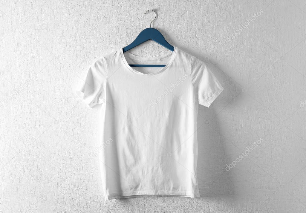 Hanger with white t-shirt on light background. Mockup for design