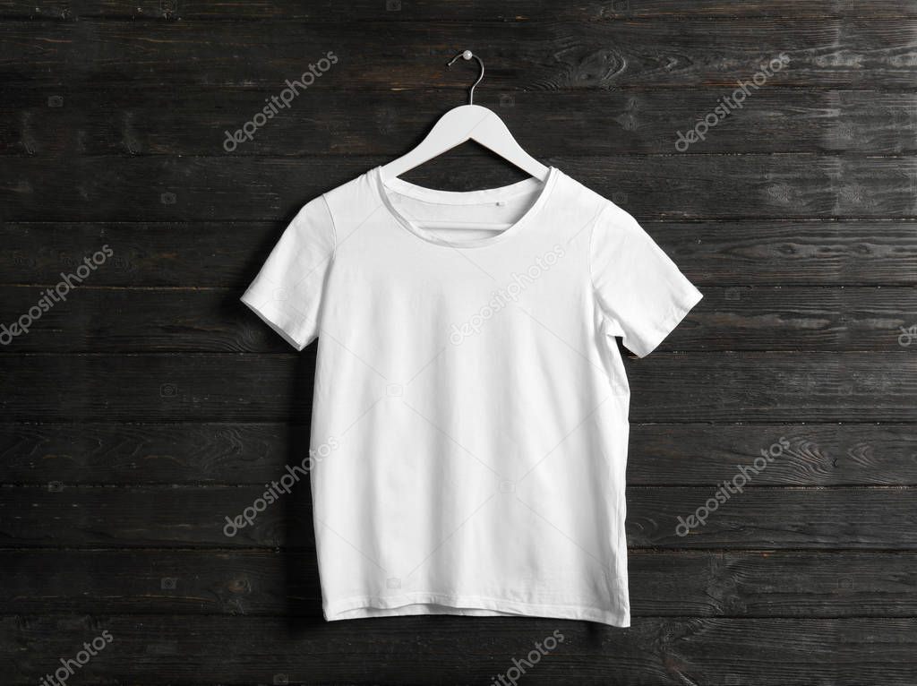 Hanger with white t-shirt on wooden background. Mockup for design