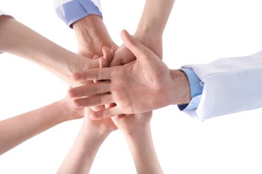 Bir grup tıp doktoru beyaz arka planda el ele tutuşuyor, yakın çekim. Birlik kavramı
