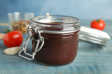 Mavi ahşap masa üzerinde lezzetli barbekü soslu kavanoz