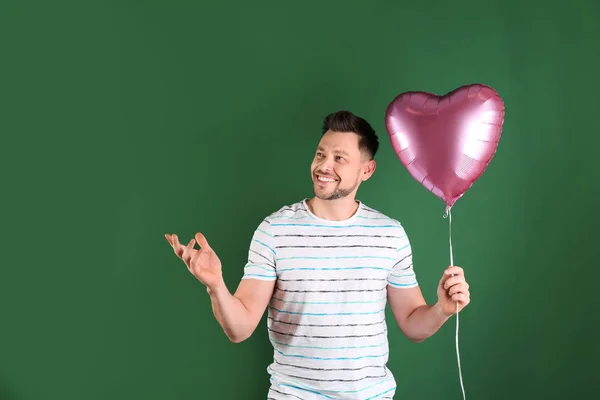 Ritratto di giovane uomo con palloncino a forma di cuore su sfondo di colore — Foto Stock
