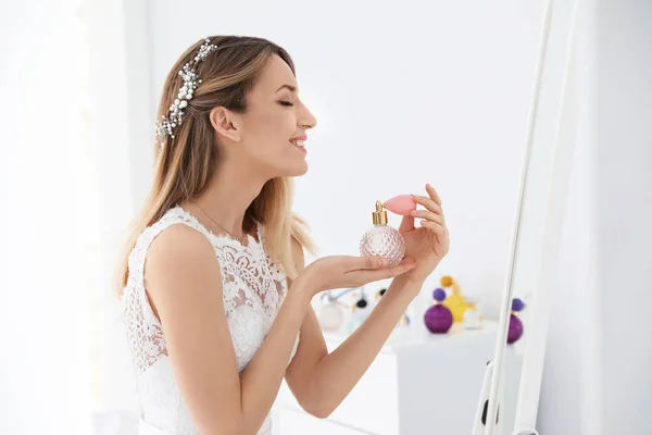 Bella giovane sposa con bottiglia di profumo vicino specchio all'interno — Foto Stock