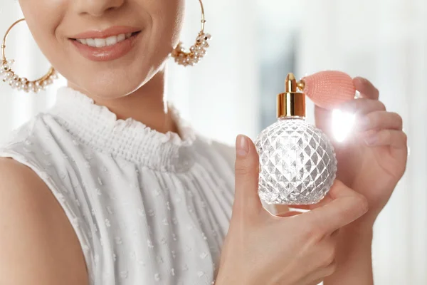 Young woman applying perfume against blurred background, closeup — Stock Photo, Image