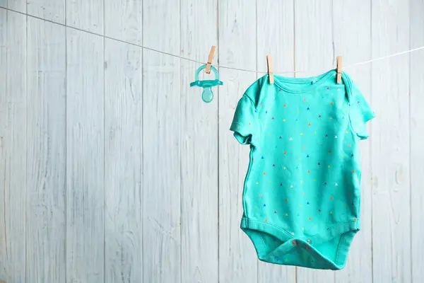Accesorios para bebés en la línea de lavandería contra fondo de madera. Espacio para texto —  Fotos de Stock
