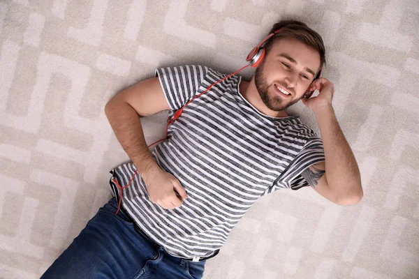 Young man in headphones enjoying music on floor, top view — Stock Photo, Image