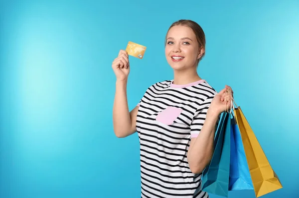Porträt einer glücklichen jungen Frau mit Kreditkarte und Einkaufstaschen auf farbigem Hintergrund, Platz für Text. Geld ausgeben — Stockfoto