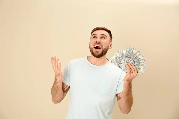 Portrait of emotional young man with money on color background — Stock Photo, Image