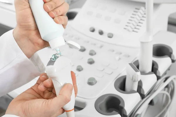 Sonographer covering ultrasound machine probe with gel in clinic, closeup — Stock Photo, Image