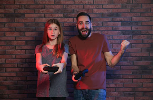 Hombre joven y adolescente jugando videojuegos con controladores cerca de la pared de ladrillo —  Fotos de Stock