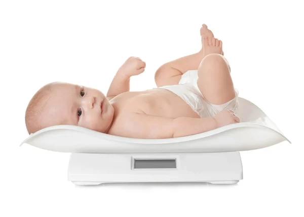 Cute little baby lying on scales against white background — Stock Photo, Image