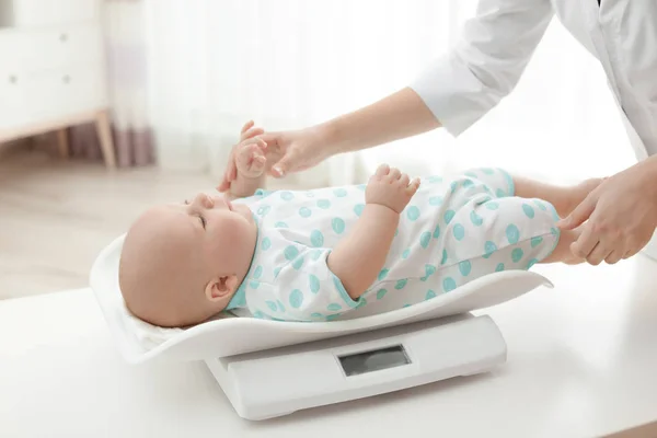 Lekarz wagi dziecka na skale w jasnym pomieszczeniu — Zdjęcie stockowe