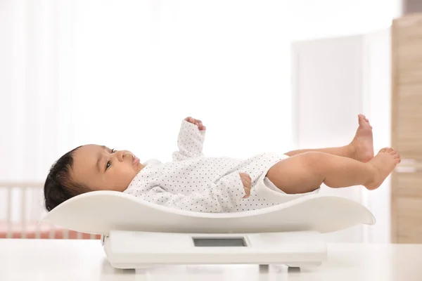 Afrikanisch-amerikanisches Baby liegt auf Waage im hellen Raum — Stockfoto
