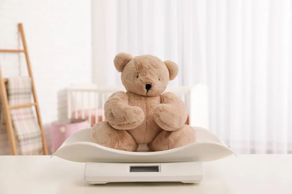 Escamas de bebé con oso de peluche en la mesa en la sala de luz —  Fotos de Stock