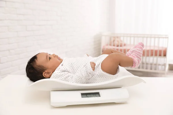 Afrikanisch-amerikanisches Baby liegt auf Waage im hellen Raum — Stockfoto