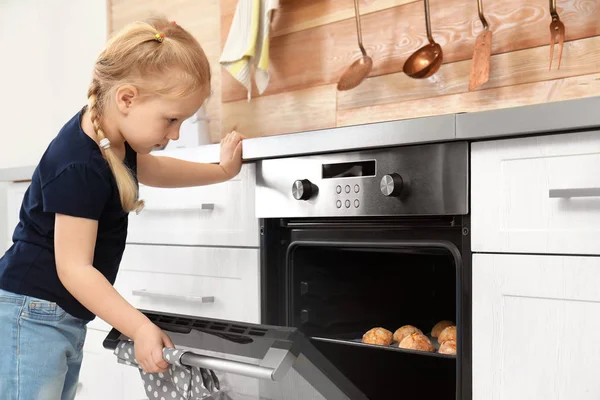 Menina verificando biscoitos no forno em casa — Fotografia de Stock