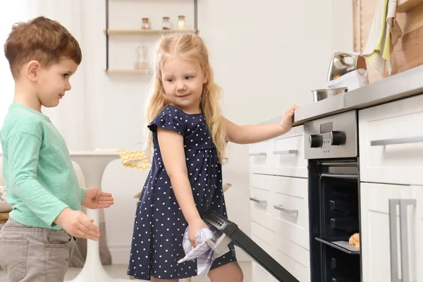 Anak-anak lucu memanggang kue di oven di rumah — Stok Foto