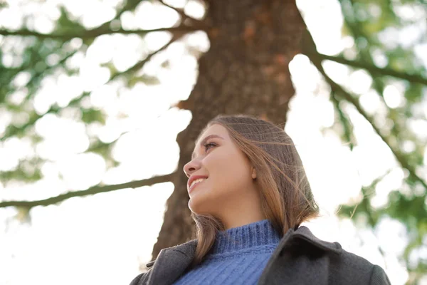 Retrato de una hermosa mujer joven cerca del árbol en el día soleado, vista de ángulo bajo — Foto de Stock