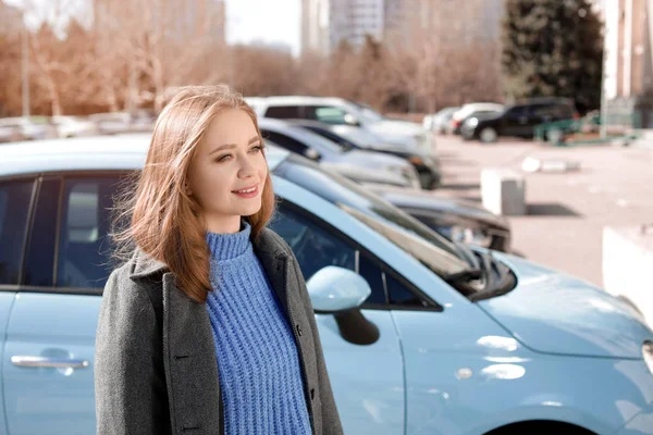 Retrato de una hermosa mujer joven cerca de coches estacionados en un día soleado — Foto de Stock