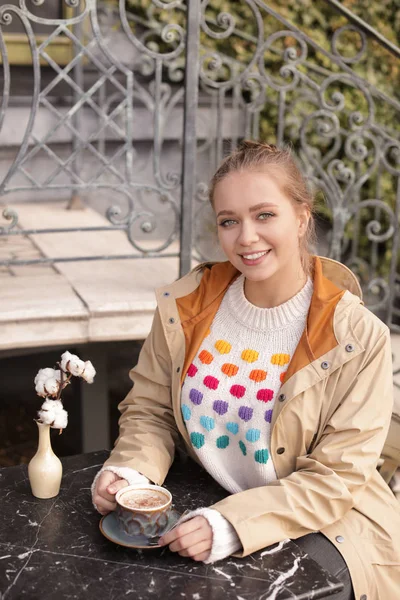 Fiatal nő élvezi finom kávé az asztalnál a szabadban — Stock Fotó
