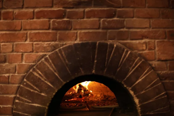 Bakstenen oven met brandende brandhout en pizza's binnenshuis — Stockfoto