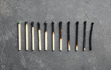 Yanmış kibrit satır ve gri arka plan üzerinde bütün bir, düz yatıyordu. İnsan yaşamı evreleri kavramı