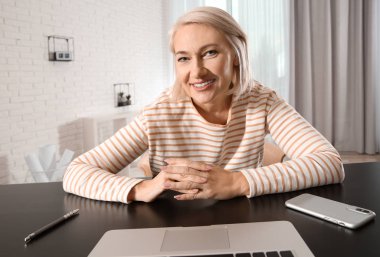 Olgun kadın evde dizüstü bilgisayarda görüntülü sohbet kullanarak, web kameradan görüntülemek