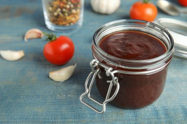 Mavi ahşap masa üzerinde lezzetli barbekü soslu kavanoz. Metin için alan