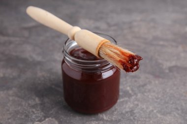Gri arka planda barbekü soslu kavanoz ve fırça