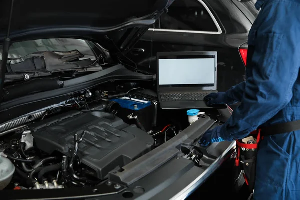 Técnico verificando carro com laptop na oficina de reparação de automóveis — Fotografia de Stock