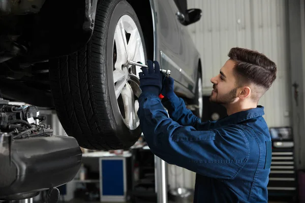 Técnico que trabalha com carro na oficina de reparação de automóveis — Fotografia de Stock