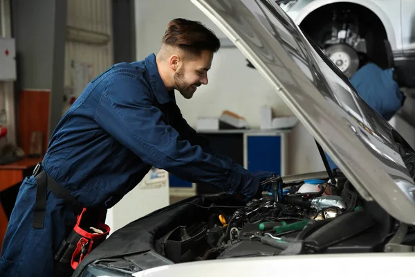 Técnico verificando carro moderno na oficina de reparação de automóveis — Fotografia de Stock