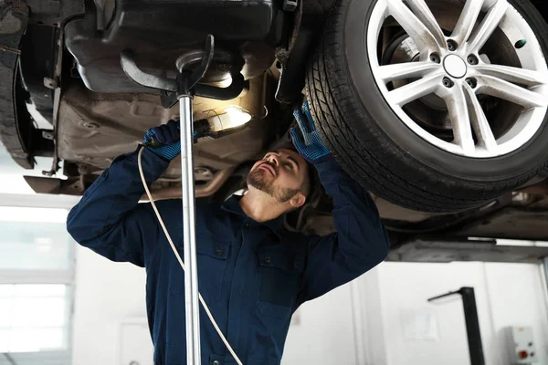 Técnico verificando carro moderno na oficina de reparação de automóveis — Fotografia de Stock