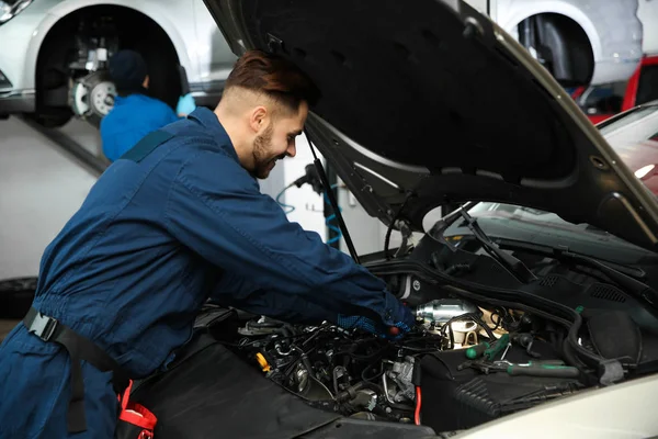 Técnico verificando carro moderno na oficina de reparação de automóveis — Fotografia de Stock