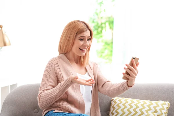 Mulher usando telefone celular para bate-papo por vídeo na sala de estar — Fotografia de Stock