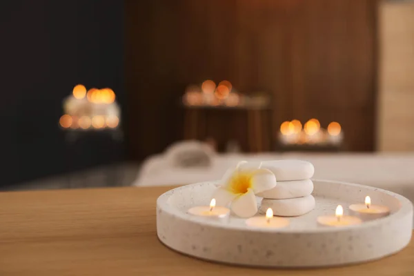 Hermosa composición con velas encendidas y piedras de spa en la mesa en el salón. Espacio para texto — Foto de Stock