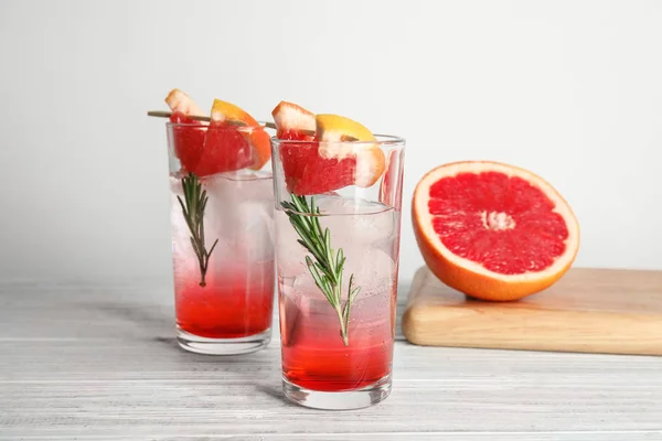 Glasses of cocktail and grapefruit half on table — Stock Photo, Image