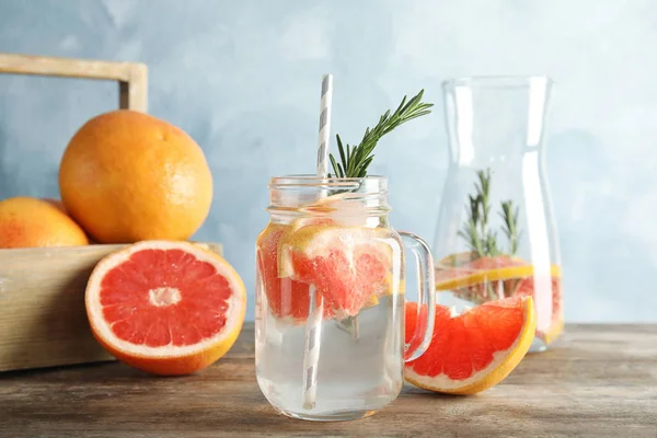 Komposition med Mason jar av infunderas vatten och grapefrukter på bordet — Stockfoto