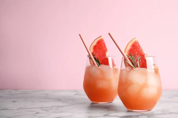 Стаканы грейпфрутовых коктейлей на столе на цветном фоне. Пространство для текста — стоковое фото