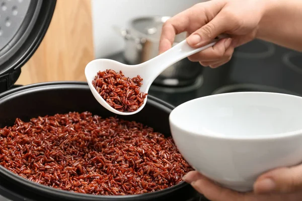 Mujer poniendo arroz integral en un tazón de cocina múltiple en la cocina, primer plano — Foto de Stock