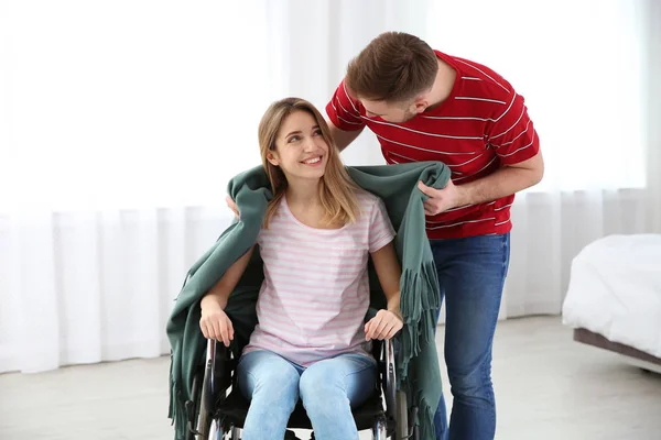 Mężczyzna obejmujący kobietę na wózku inwalidzkim z kratą w domu. Pomaganie niepełnosprawnym — Zdjęcie stockowe